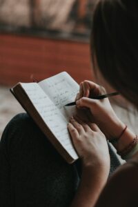 Main écrivant dans un carnet pour poser ses pensées et alléger sa charge mentale
