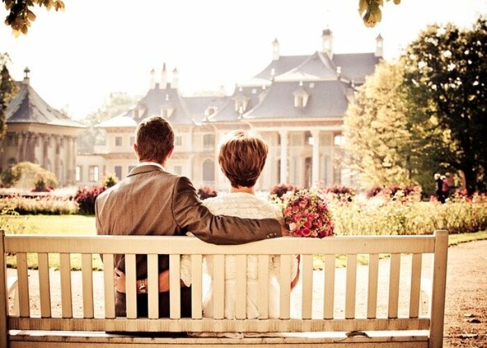 Couple assis sur un banc, vu de dos, dans un jardin baigné de lumière dorée