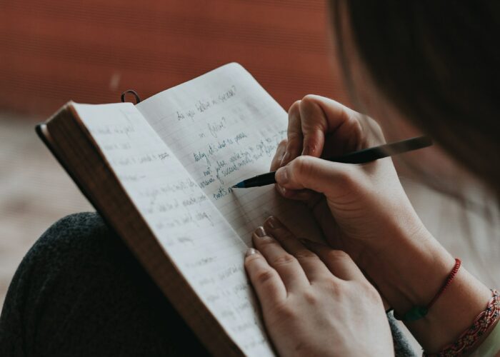 Main écrivant dans un carnet pour poser ses pensées et alléger sa charge mentale